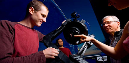 Students and professor working with a telescope.