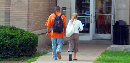 Two students walking into a campus building.