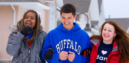 Three students walking and laughing outside in the winter.